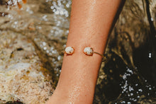 Freshwater Pearl Bangle in gold in the ocean.