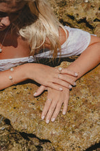 Close up shot of model wearing Freshwater Pearl pieces on the rocks. 