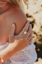 Close up of model with Freshwater Peal ring on her finger, wearing a white lace dress.