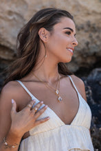 Model wearing two Higher Realm Herkimer Diamond Crystal Necklaces in gold, paired with gold rings, thread earrings, and a bangle, set against a rocky backdrop, highlighting the natural beauty and elegance of the collection.