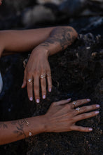 Model’s hands on a dark rocky background showcasing the Higher Realm Herkimer Diamond rings in gold, paired with a matching Herkimer Diamond bangle, highlighting the elegance and brilliance of the Herkimer diamonds.