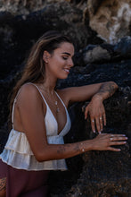 Model standing with dark rock background, wearing Herkimer Diamond rings in gold, matching bangle, necklace, and stud earrings.