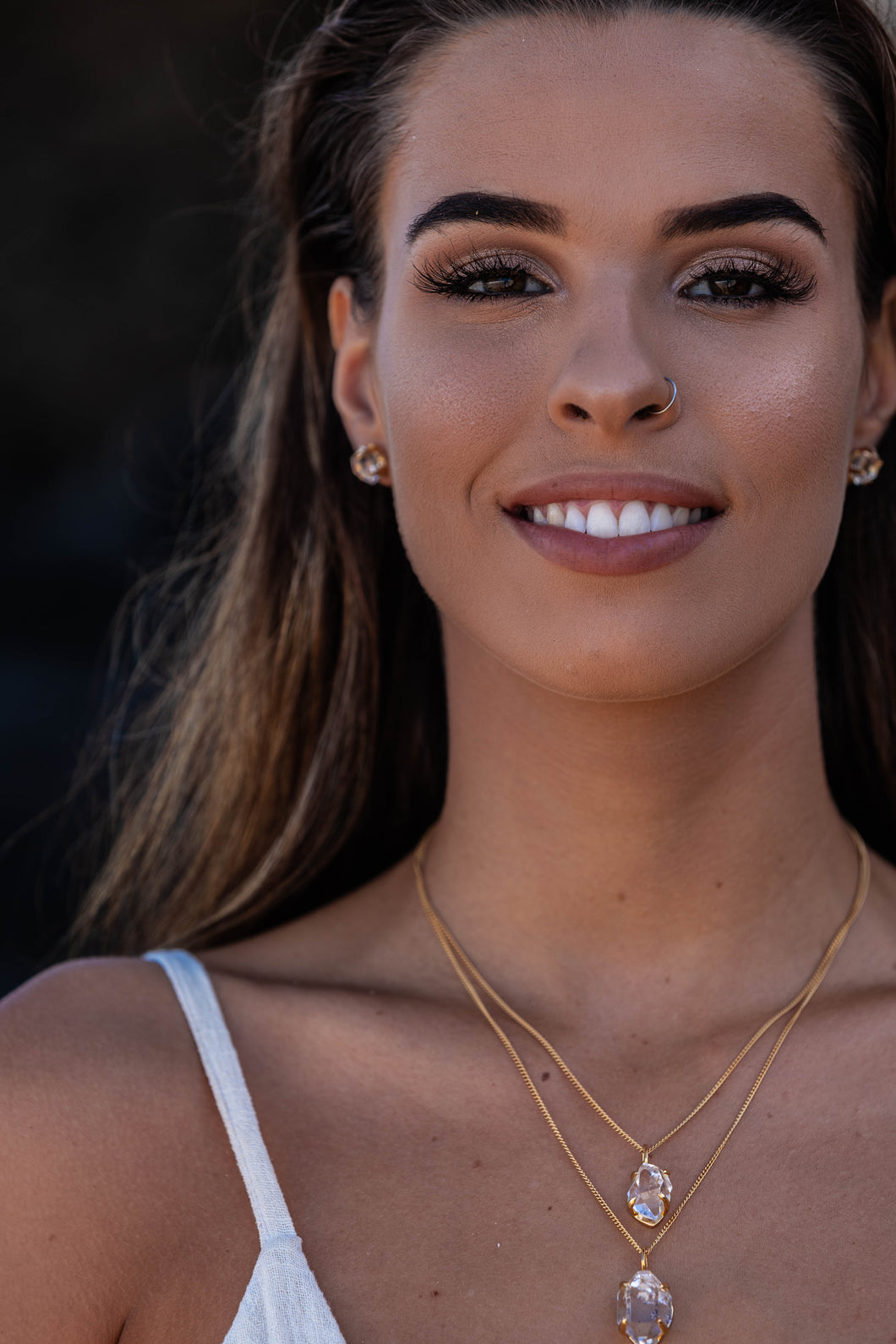 Close-up of the model wearing two Higher Realm Herkimer Diamond Crystal Necklaces in gold around her neck, paired with matching stud earrings, highlighting the clarity and brilliance of the Herkimer diamonds.