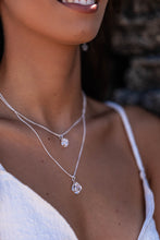 Close-up of the Higher Realm Herkimer Diamond Crystal Necklaces in silver, worn by the model with a blurred rocky backdrop, highlighting the clarity and shine of the Herkimer diamonds.