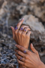 Extreme close-up of the model’s hands adorned with five Violet Horizon Amethyst crystal rings in gold, highlighting the raw beauty and intricate details of the crystals.