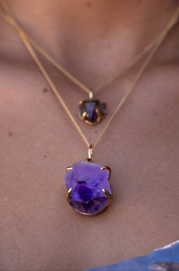 Close-up of a model wearing a Violet Horizon Amethyst crystal necklace with large and small amethyst stones set in gold, highlighting the intricate details of the design.