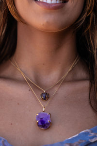 Close-up of a model wearing the Violet Horizon Amethyst crystal necklace, featuring large and small amethyst stones set in gold.