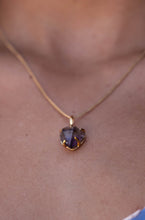 Extremely close-up of the small Violet Horizon Amethyst crystal necklace in gold, resting elegantly on the model’s neck, highlighting the amethyst stone.