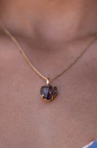 Extremely close-up of the small Violet Horizon Amethyst crystal necklace in gold, resting elegantly on the model’s neck, highlighting the amethyst stone.