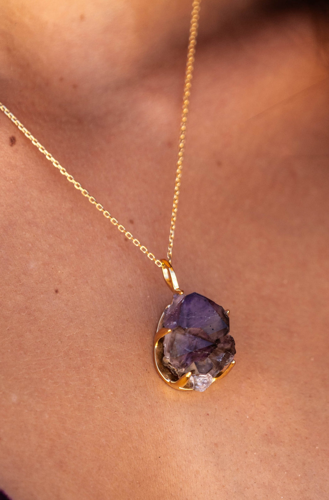 Extreme close-up of the model’s neck wearing the Twilight Veil Amethyst Crystal Cluster Necklace in gold, focusing solely on the necklace, highlighting the raw amethyst clusters.