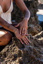 Model’s hands resting on a rock formation, wearing Herkimer Diamond rings and bangle set in gold.